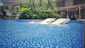 A swimming pool with blue mosaic tiles, surrounded by lush greenery and a modern building in the background. - R&F Seine Region (Johor Bahru)