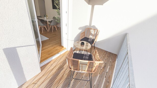 Una terraza de madera con sillas de mimbre y una mesa de vidrio, que da paso a un comedor interior con una mesa y sillas.