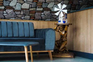 A modern interior with a stone wall, a blue sofa, and a wooden statue. - Oscar Seaside Hotel & Spa (Bodrum)