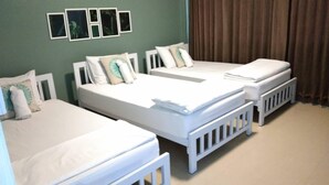 A hotel room with two single beds, white bedding, and a green wall with framed pictures. - Sleepcase Hostel (Bangkok)