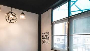 A modern interior with a staircase, a sign reading "RECREATION PLACE", and a view through a large window.