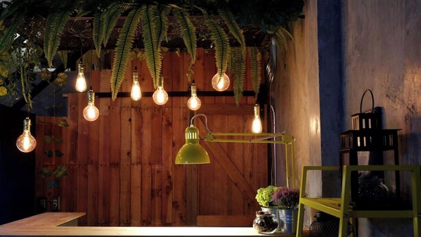 A rustic interior with wooden walls, hanging light bulbs, and a green desk lamp. - Sleepcase Hostel (Bangkok)