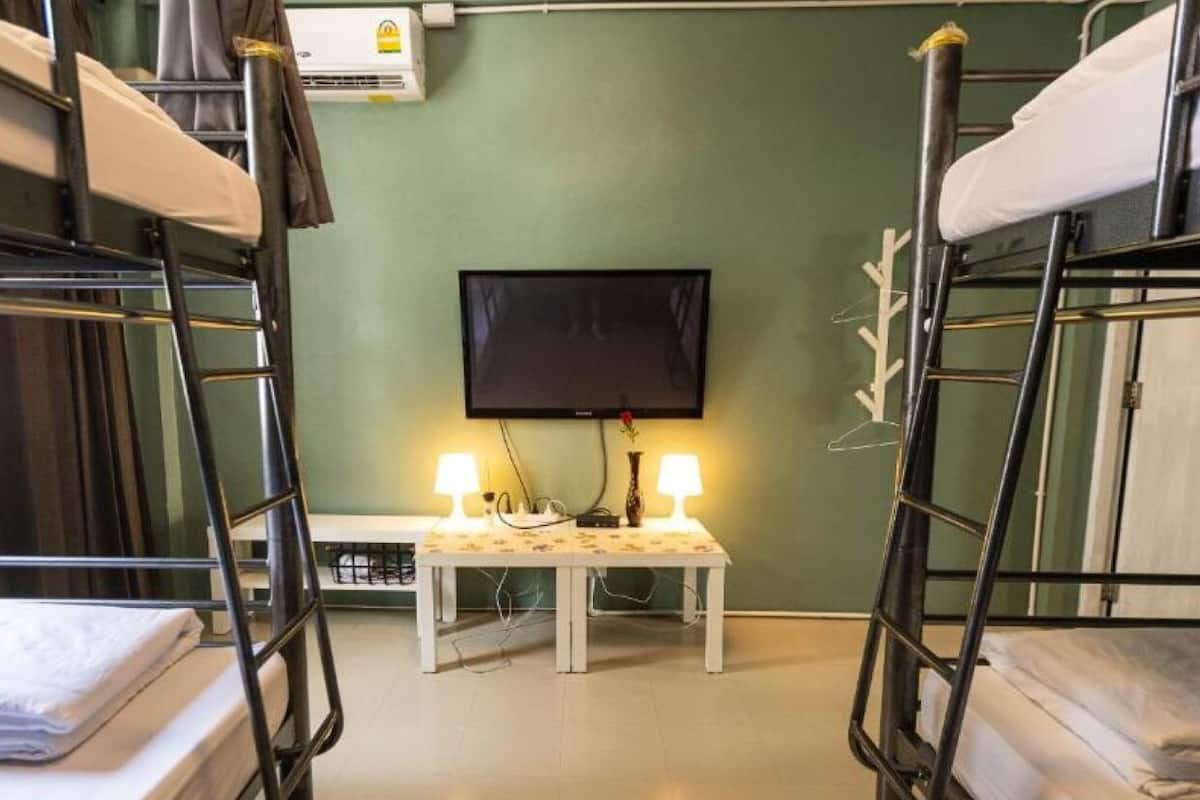 A bunk room with two beds, a television, and a small table with lamps.