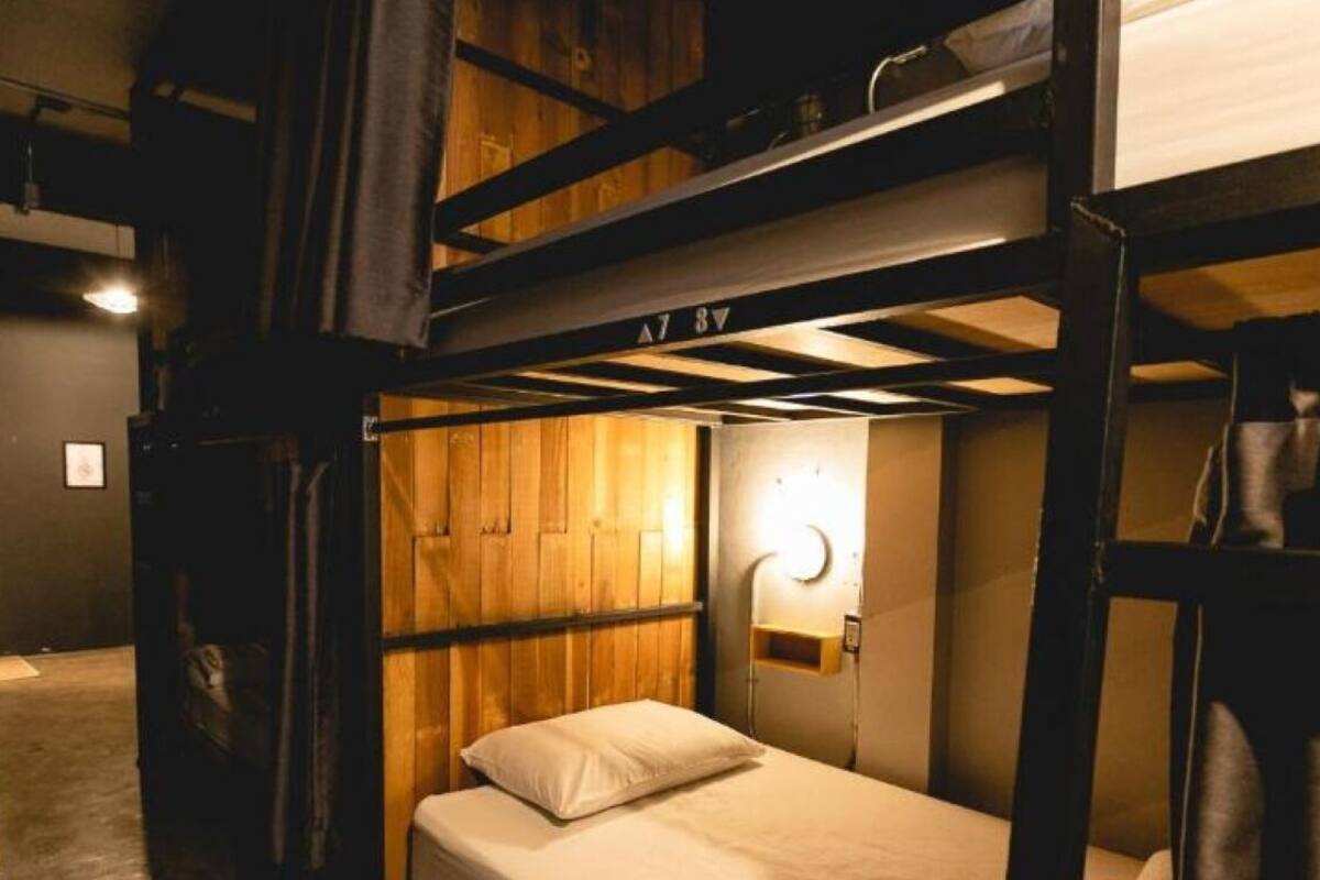 A bunk bed room with a wooden headboard, a bedside lamp, and a small shelf.