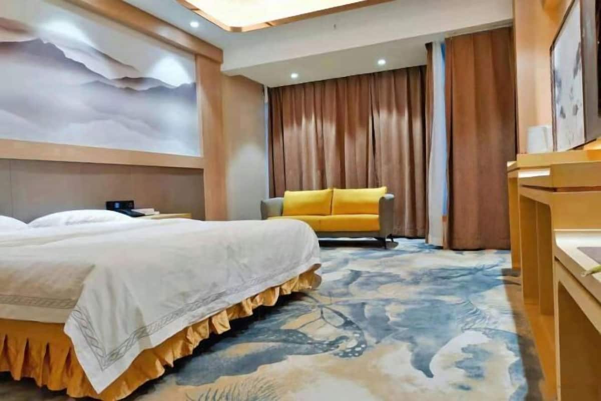 Habitación de hotel con una cama grande, un sofá, un escritorio y un mural en la pared.