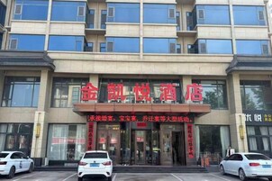 Un hotel con un letrero rojo llamativo, varios pisos y un estacionamiento lleno de coches.