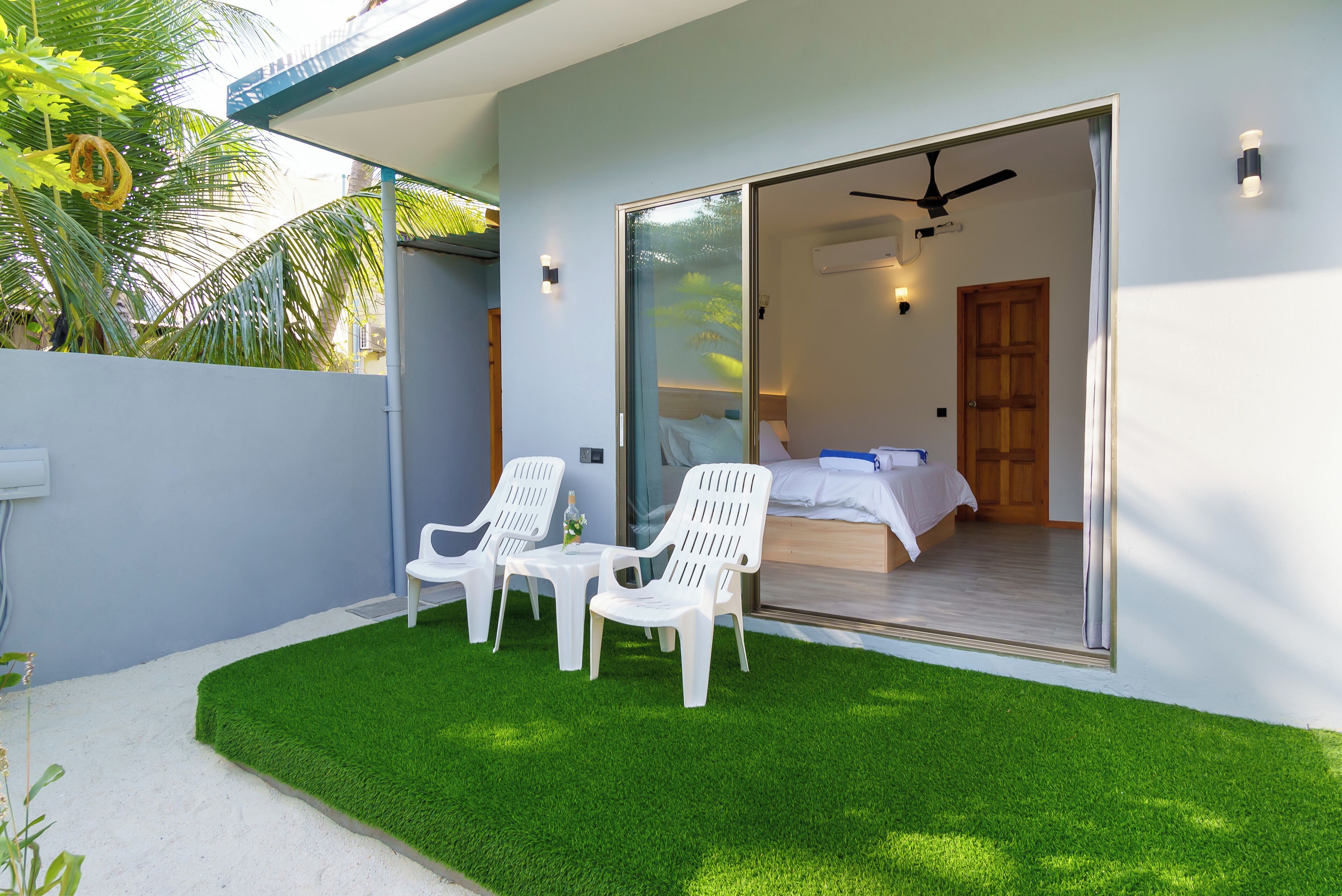 A bedroom with a sliding glass door, a ceiling fan, and a bed with white linens.