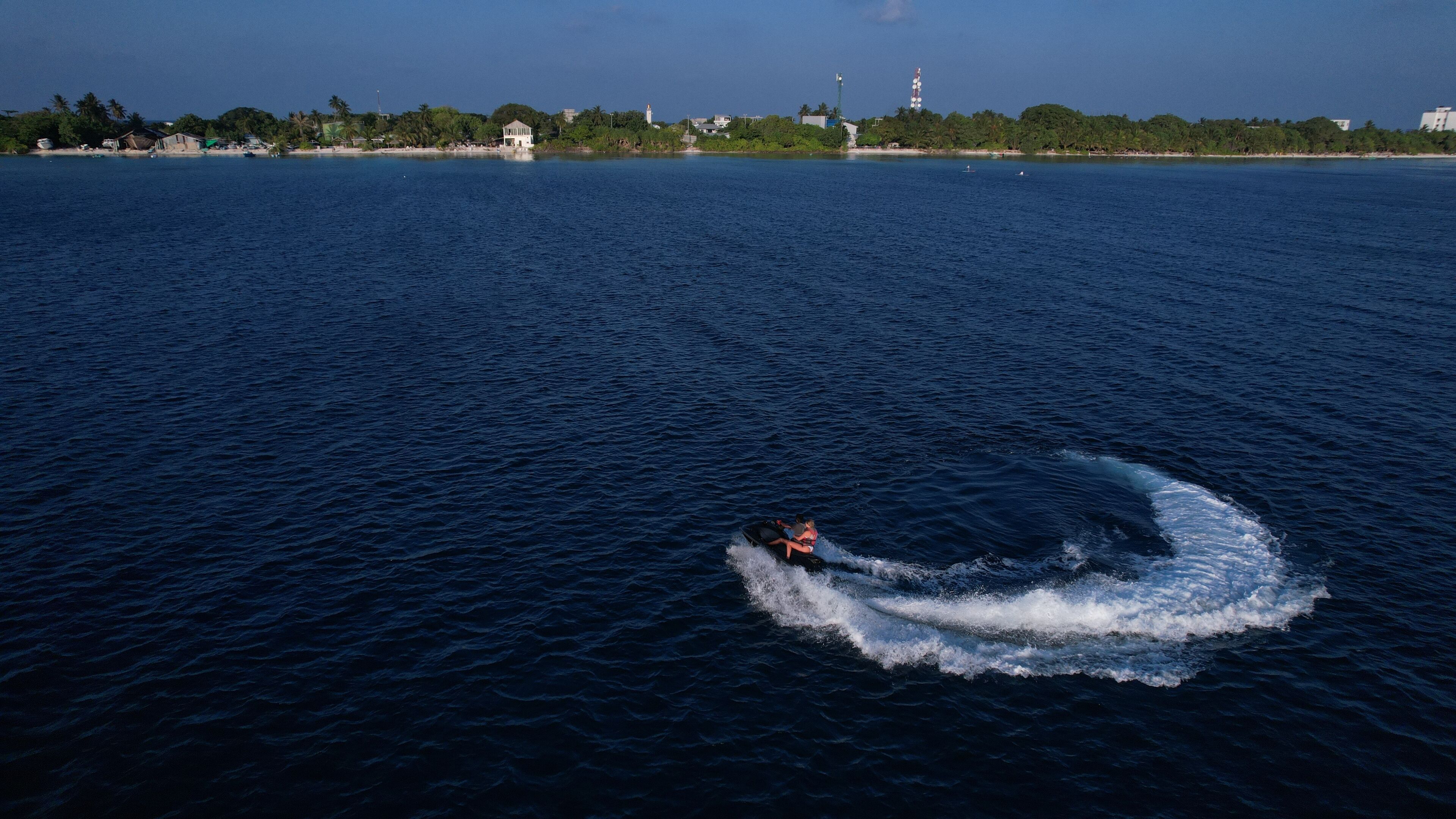 A jet ski on a calm body of water with a distant shoreline featuring buildings and trees.
