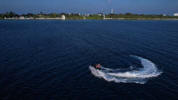 A jet ski on a calm body of water with a distant shoreline featuring buildings and trees.