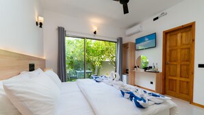 A hotel room with a large bed, a ceiling fan, a TV, a wooden door, and a window with curtains. - La Solara Villa (Ukulhas)