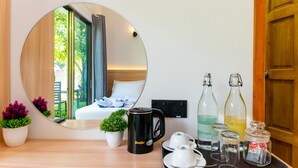 A hotel room with a round mirror reflecting the bed and window, a coffee maker, two cups, two bottles, and a tray with glasses and a jar. - La Solara Villa (Ukulhas)
