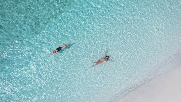 Vista aérea de una playa con agua turquesa cristalina y arena blanca.