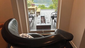 Une pièce avec vue sur un lac et des montagnes, accessible par une porte vitrée.
