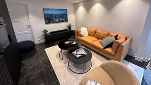 Un salon moderne avec un canapé, une table basse et un téléviseur fixé au mur.