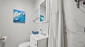 Un baño con inodoro, lavamanos y cortina de ducha.
