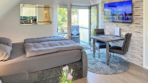 Ein modernes Schlafzimmer mit einem großen Bett, einem Esstisch und einem an einer Steinwand befestigten Fernseher.