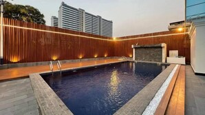 A swimming pool with a wooden fence and a stone border, surrounded by a paved deck. - Phat Power Hotel (Sihanoukville)