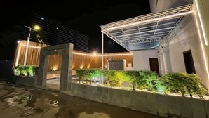 A modern building with a covered outdoor area, concrete structures, and illuminated plants. - Phat Power Hotel (Sihanoukville)