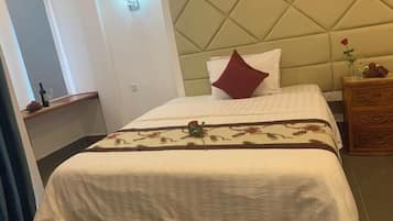 A hotel room with a bed, a nightstand, and a wooden dresser.