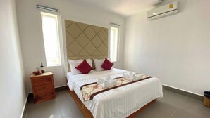 A bedroom with a bed, a wooden nightstand, a window, and an air conditioning unit. - Phat Power Hotel (Sihanoukville)