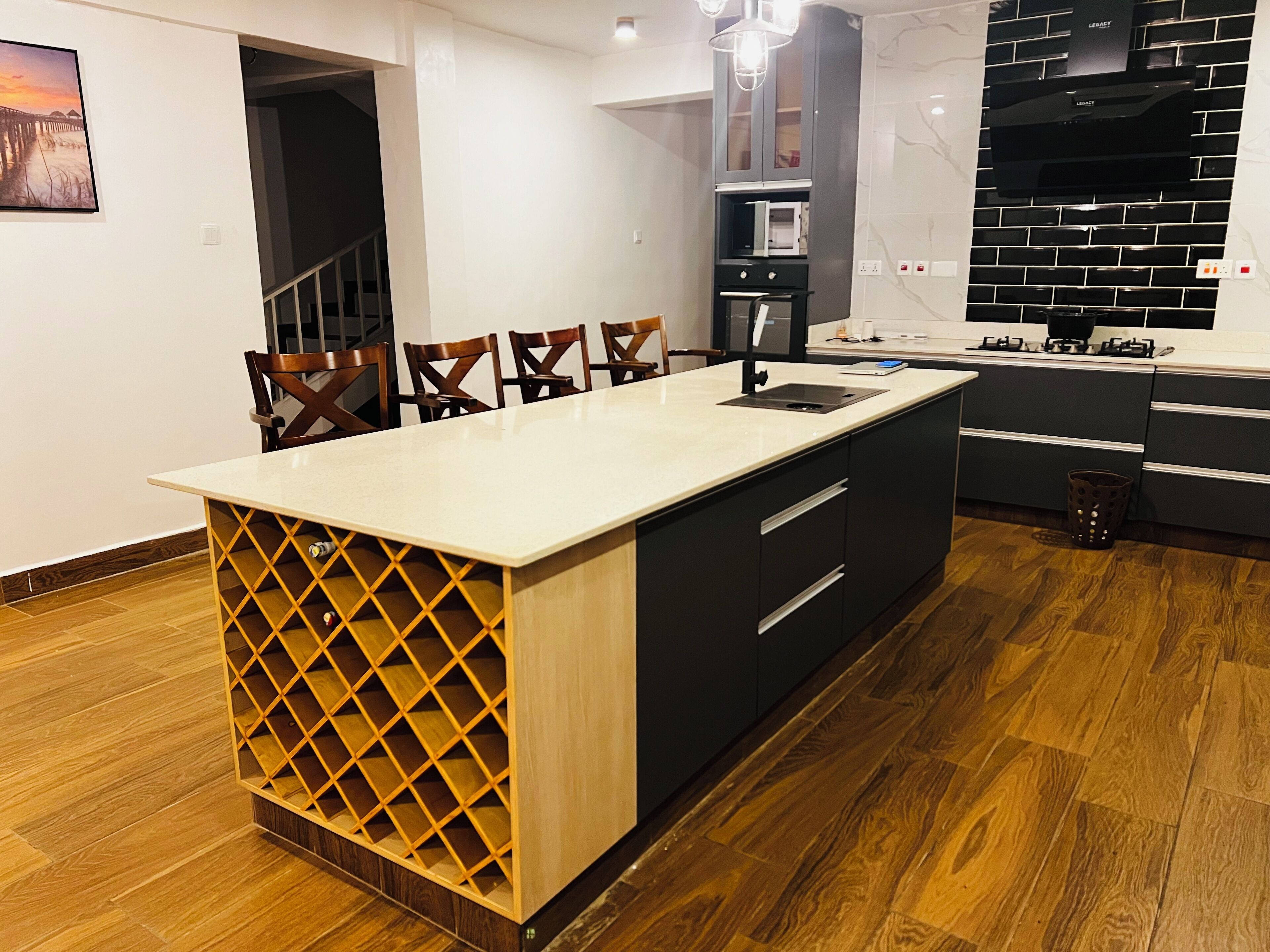 Una cocina moderna con una isla central, armarios negros y suelo de madera.