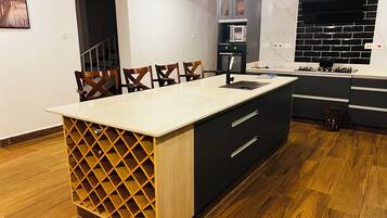 Una cocina moderna con una isla central, armarios negros y suelo de madera.