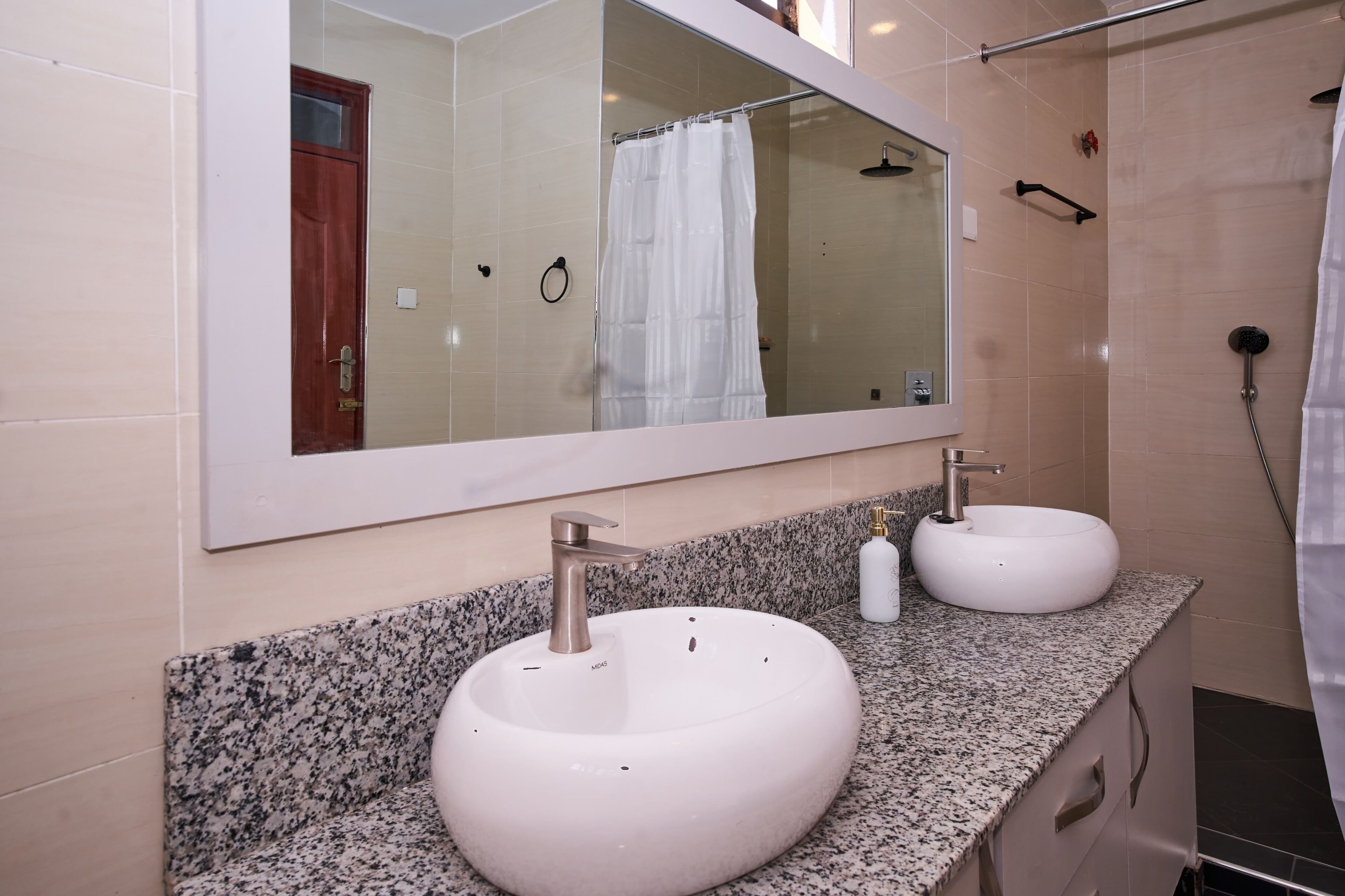 Ein Badezimmer mit zwei Waschbecken, einem großen Spiegel und einer Duschkabine.