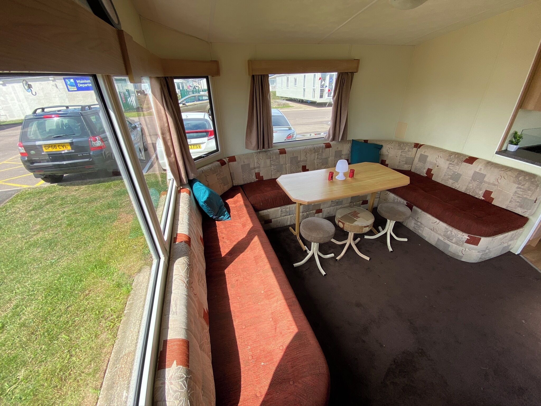 A compact RV interior with a dining area, seating, and a view of the outside.