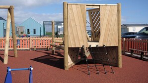 A playground with wooden climbing structures and a red rubberized surface. - GC132 - Discover Your Perfect Seaside Escape in Clacton-on-Sea! (Saint Osyth)