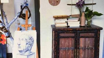 A room with a wooden cabinet, a vase with flowers, and a painting on the wall.