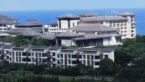 A coastal hotel with multiple buildings, including a prominent white structure with a curved roof and a smaller building with a flat roof. - Weifudun Holiday Apartment (Hailing Island Poly Silver Beach) (Yangjiang)