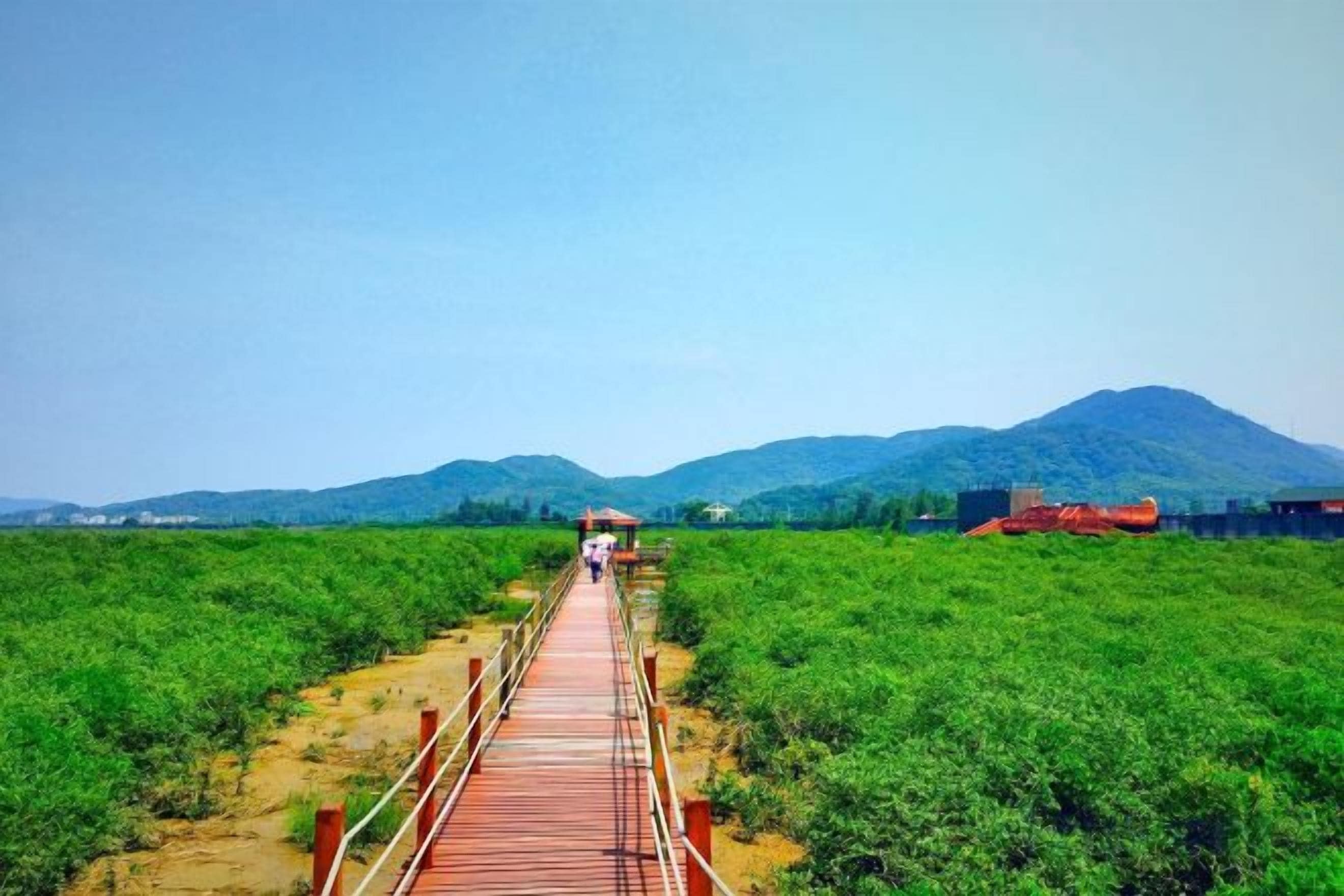 A wooden bridge leading to a structure with a view of a mountain.
