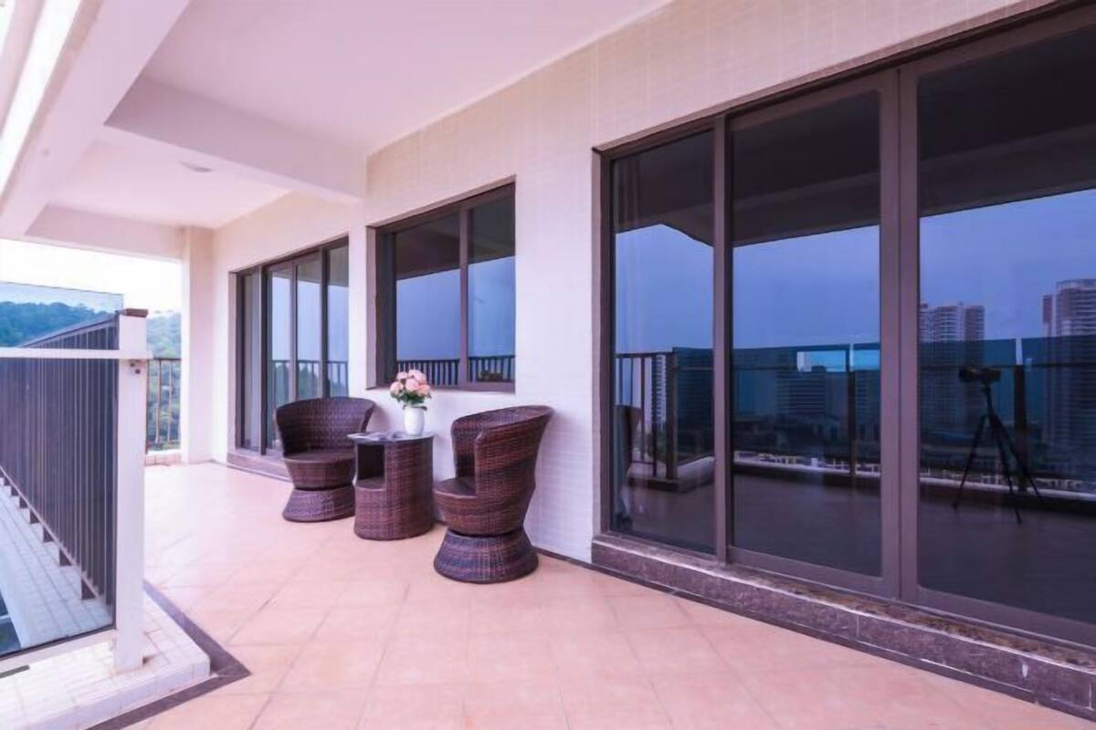 Un balcón con amplias ventanas, muebles de mimbre y un trípode.