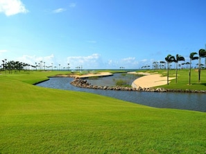 A golf course with a water hazard, sand bunkers, and a clear sky. - Weifudun Holiday Apartment (Hailing Island Poly Silver Beach) (Yangjiang)