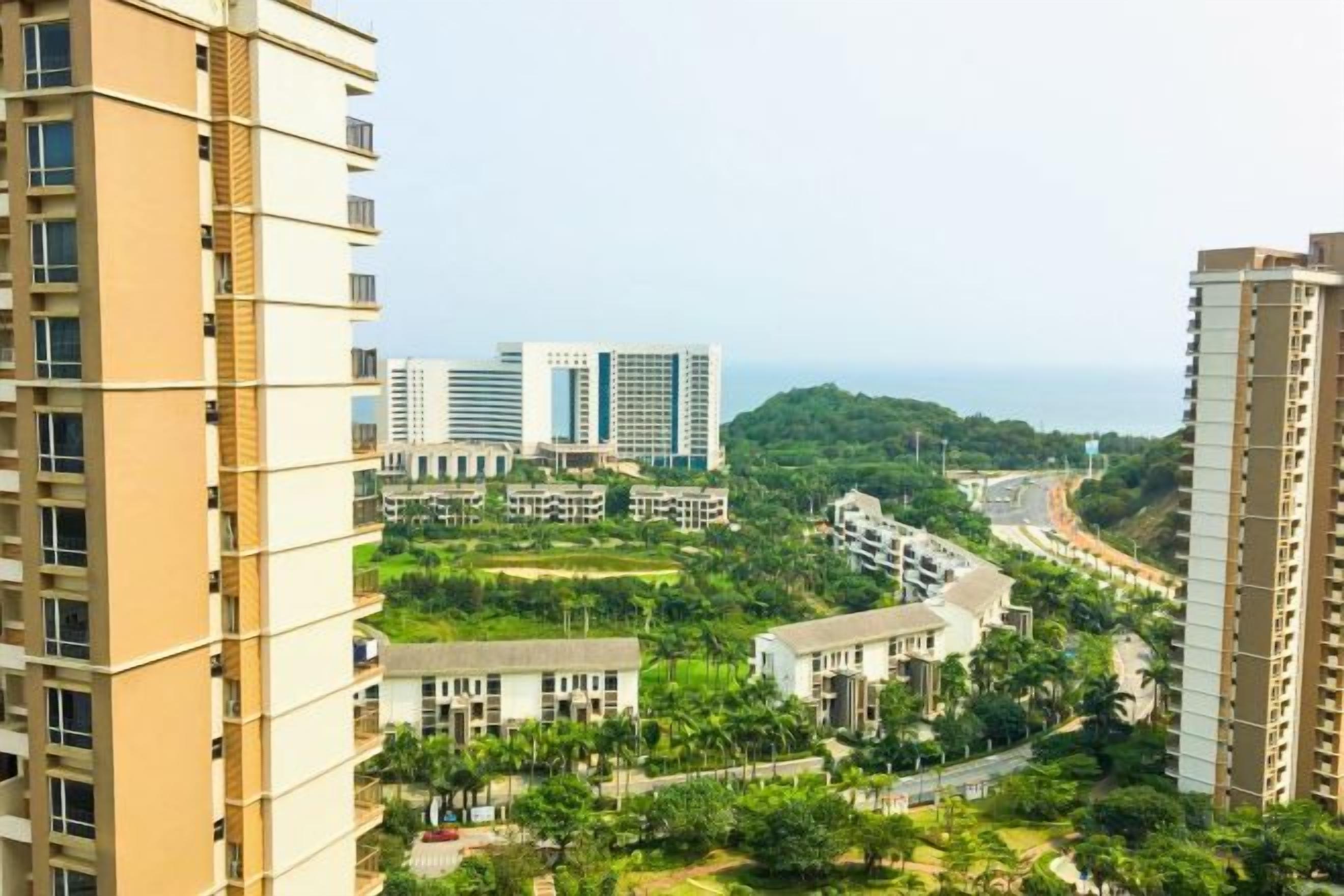 A high-rise building with multiple floors, surrounded by greenery and other buildings.
