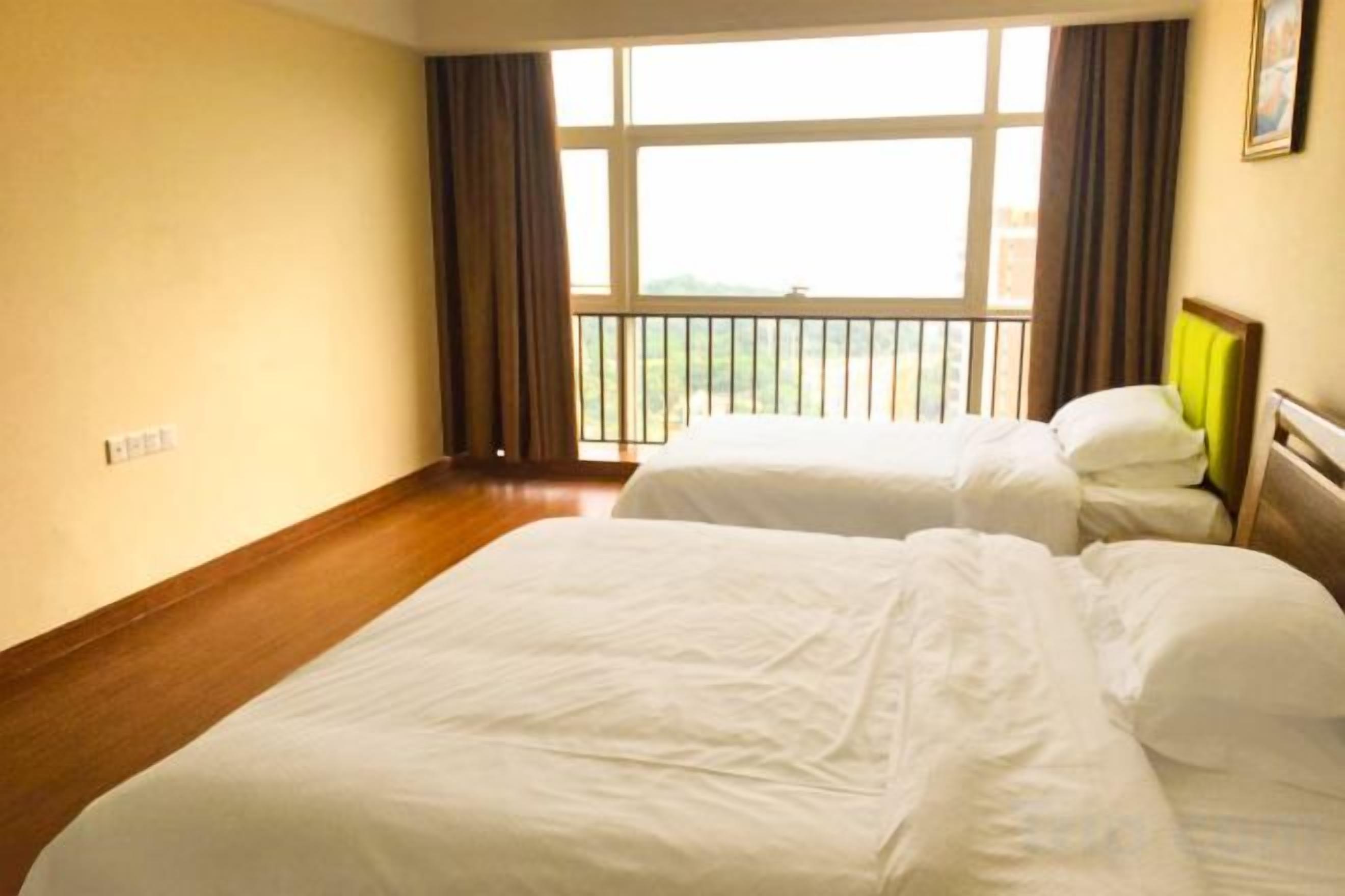A hotel room with two beds, a large window with curtains, and a wooden floor.