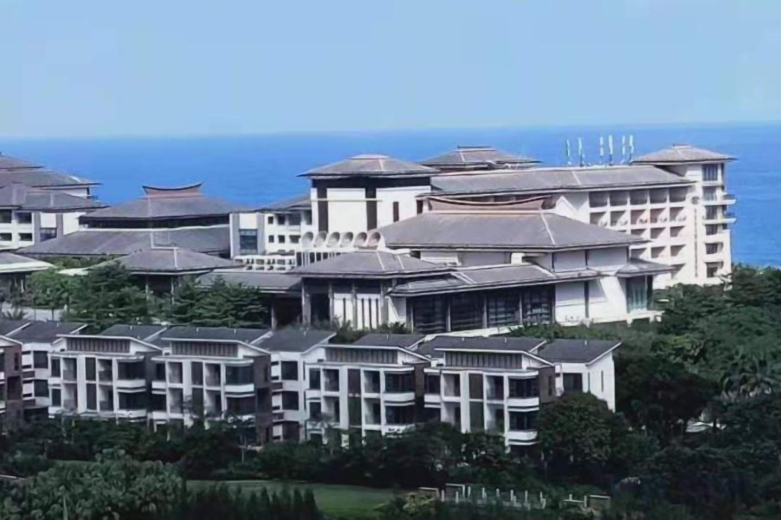 Un hotel con varias edificaciones, incluyendo una estructura blanca destacada con techo plano y un edificio más pequeño con techo curvo.