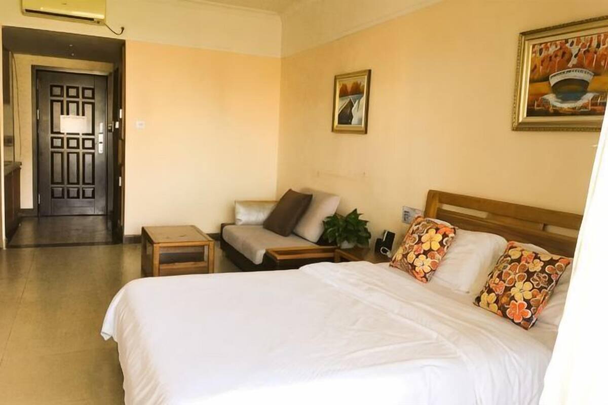 Una habitación de hotel con cama, sofá, una mesita y una puerta que da a otra habitación.