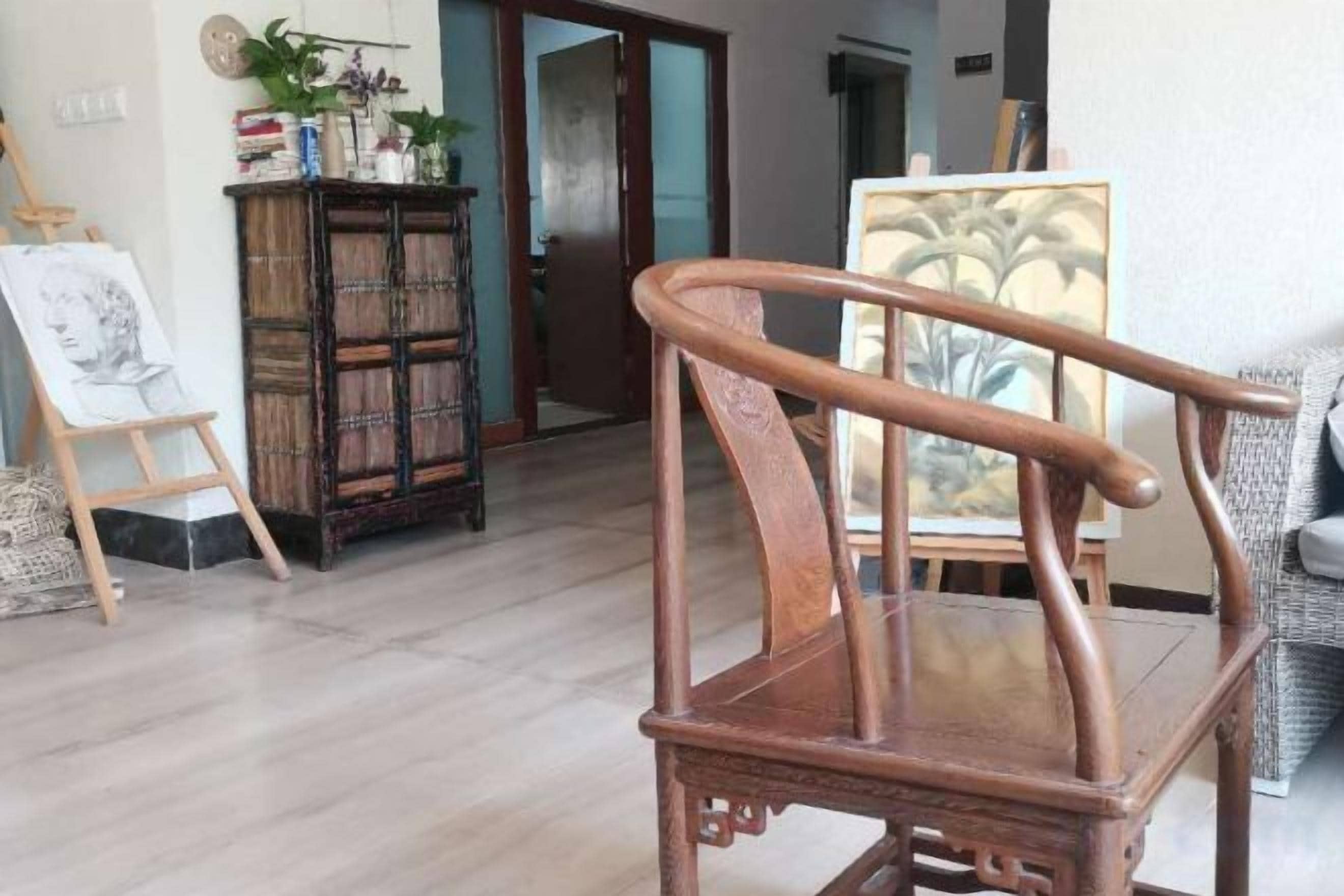 Una silla de madera en una habitación con piso de madera, un cuadro en la pared y un mueble con objetos encima.