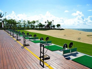 A wooden deck with exercise equipment and green mats, overlooking a sandy beach with palm trees. - Weifudun Holiday Apartment (Hailing Island Poly Silver Beach) (Yangjiang)