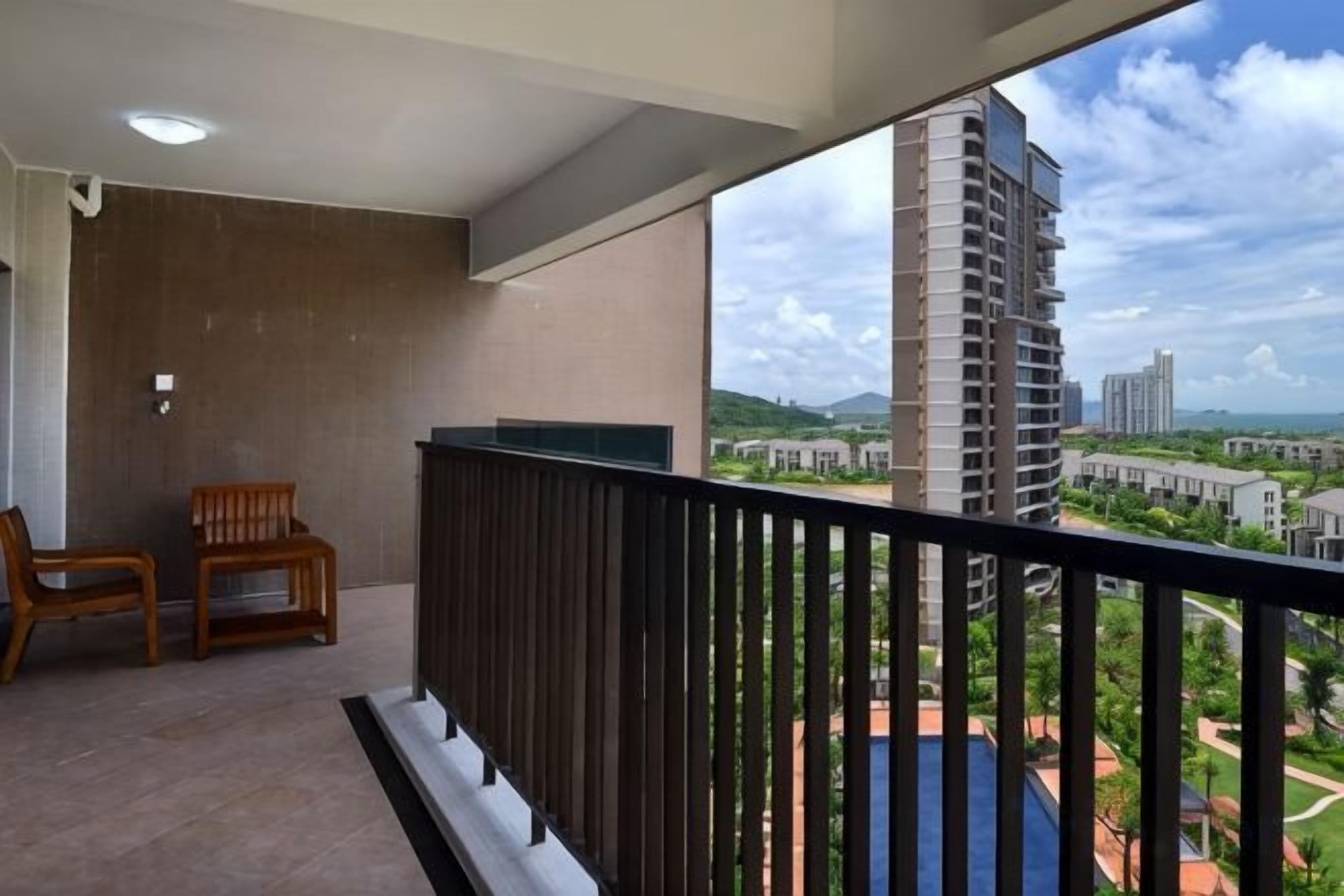 A balcony with a view of a tall building and surrounding landscape.