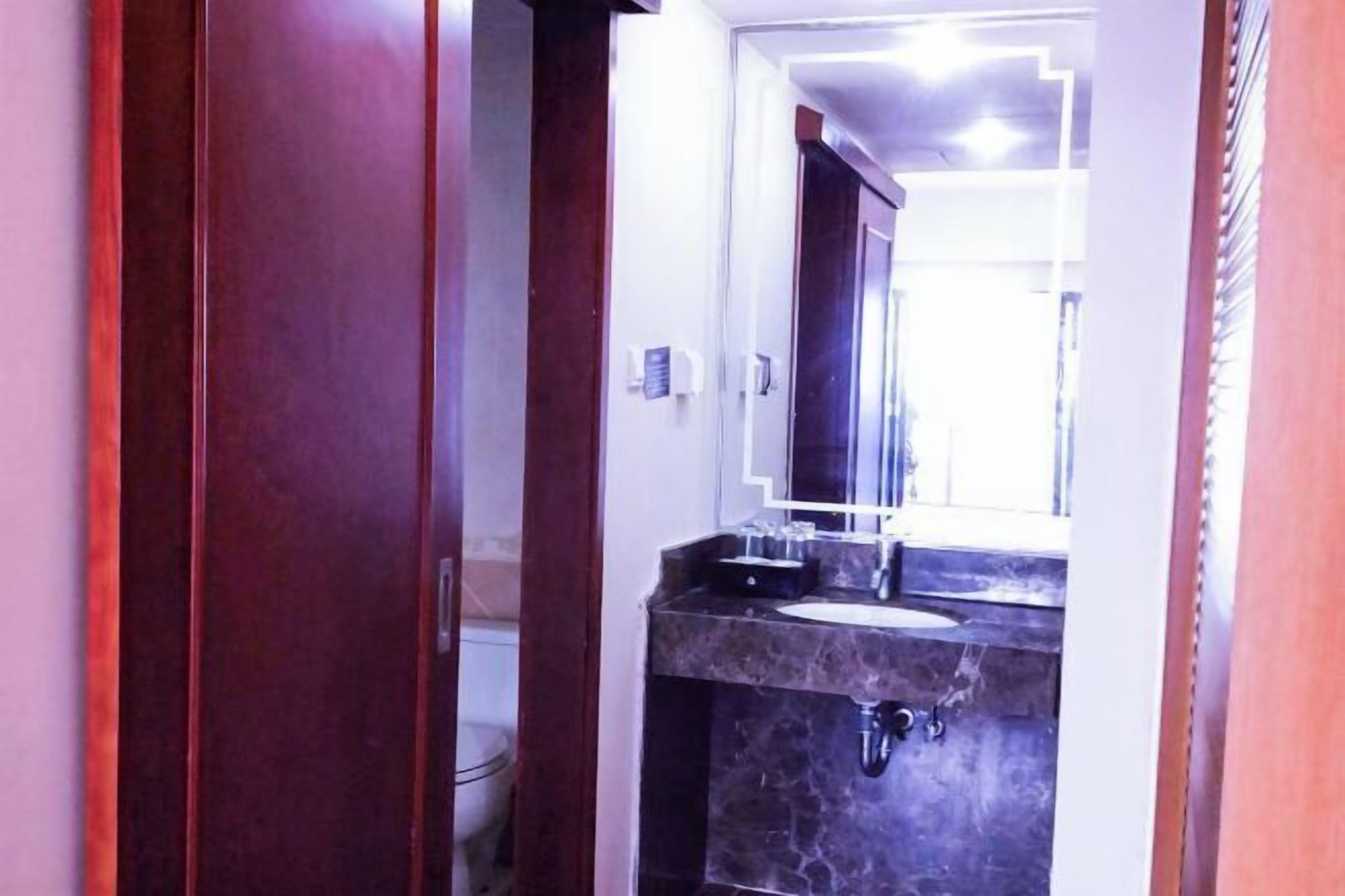 A bathroom with a marble sink, a mirror, and a wooden door.