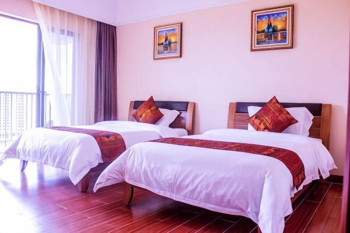 Habitación de hotel con dos camas, un balcón y dos cuadros en la pared.