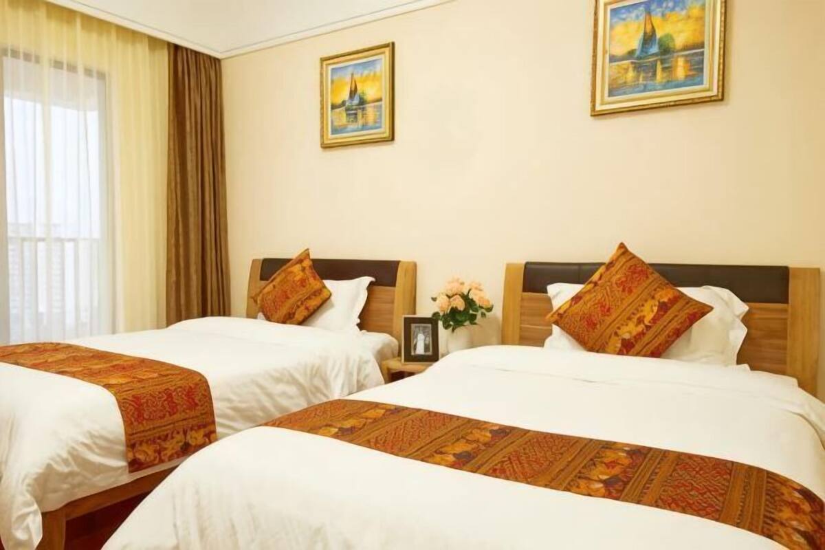 Habitación de hotel con dos camas, paredes color beige y dos cuadros enmarcados.