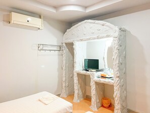 A bedroom with a bed, a desk with a computer, and a white canopy bed.