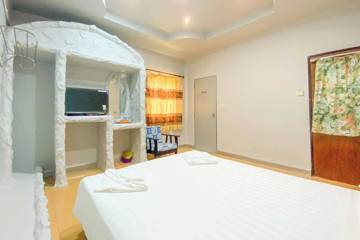Una habitación de hotel con una cama, televisión, armario y puerta.