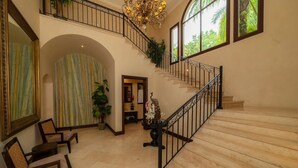 Ein geräumiges Foyer mit einer imposanten Treppe, einem großen Spiegel und einer Zimmerpflanze.