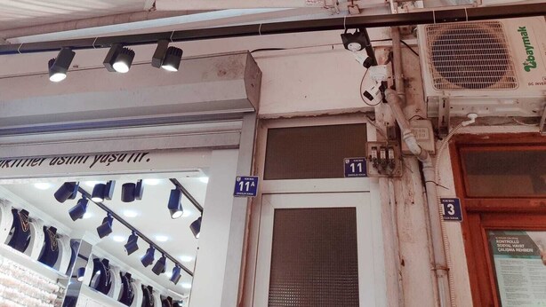 A multi-story building with a white facade, several windows, and a visible storefront with mannequins displaying clothing. - Çarşı Marin Denizer Pension (Amasra)