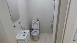A small, clean bathroom with a toilet, sink, and shower. - Çarşı Marin Denizer Pension (Amasra)