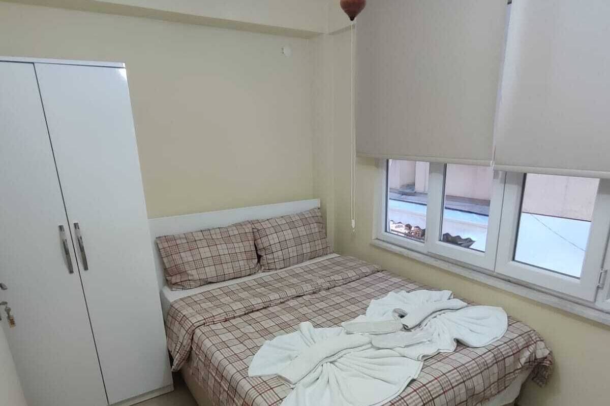 A bedroom with a bed, a wardrobe, a window with blinds, and a ceiling light.